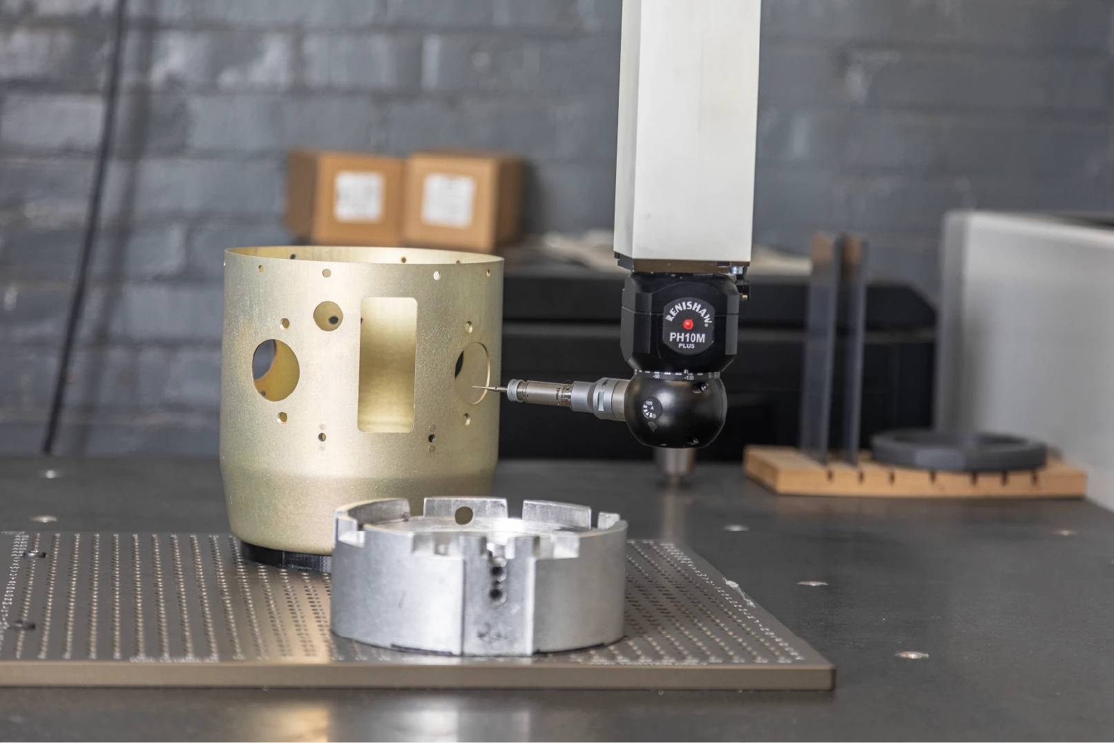 CMM probe inspecting a gold-finished machined cylindrical housing at Buckeye Shapeform.