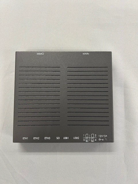 Gray metal telecommunications router enclosure with vent slots and etched port labels for Ethernet, USB, SD, and SIM
